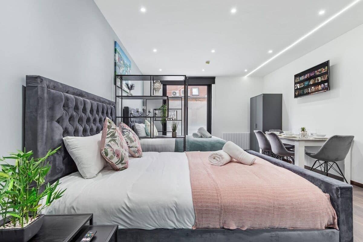 A modern bedroom with a large bed, a desk, and a dining area.