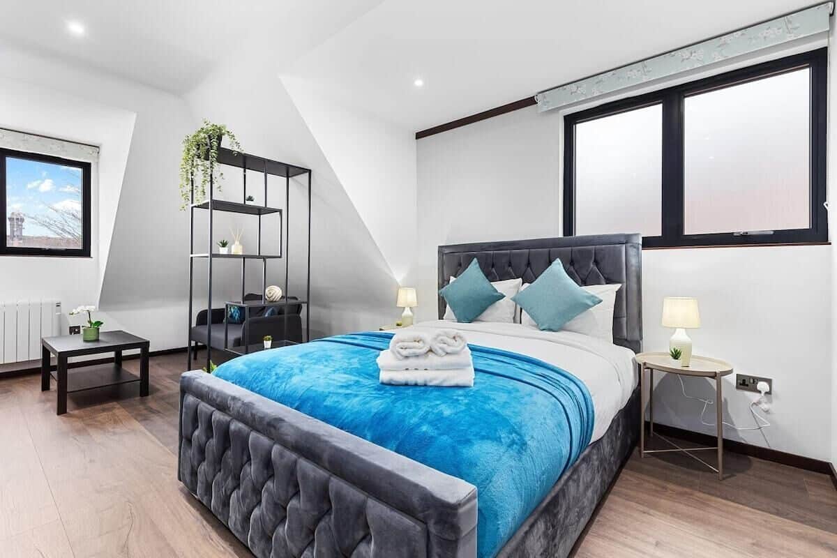 A modern bedroom with a large bed, a built-in wardrobe, a bedside table, and a window with a view.