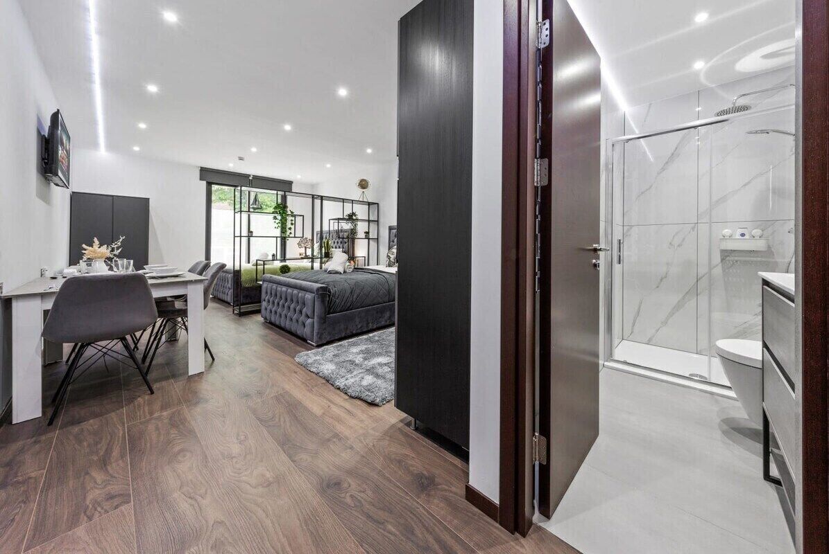 A modern hotel room with a desk, a comfortable sofa, a large bed, and a separate bathroom with a shower and toilet.
