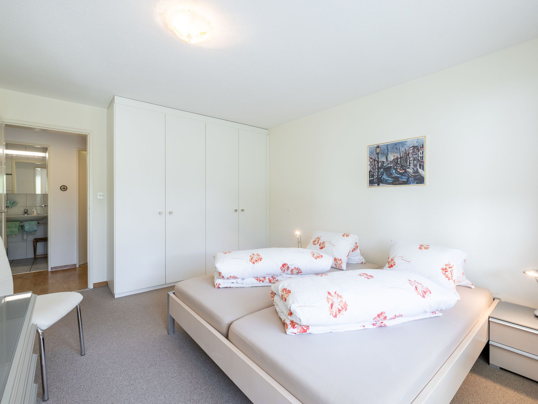 A bedroom with a bed, a nightstand, a desk, and a wardrobe.
