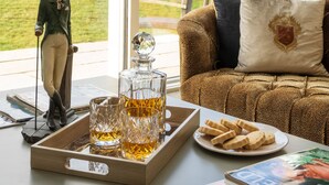 Un soggiorno accogliente con un divano, un decanter di vetro, bicchieri, biscotti e una figurina di cervo.