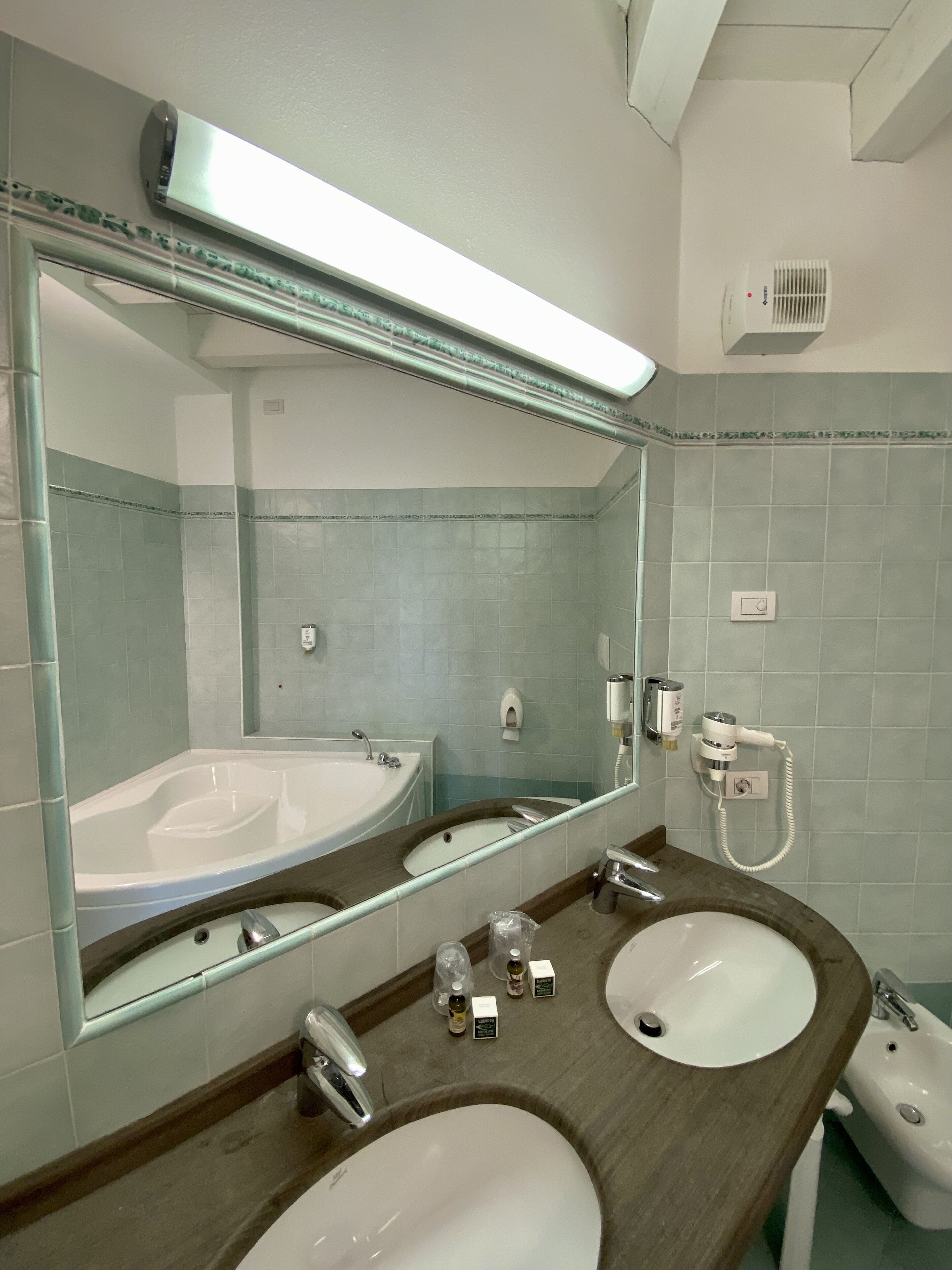 Ein Badezimmer mit zwei Waschbecken, einem großen Spiegel, einer Badewanne und einem Haartrockner.