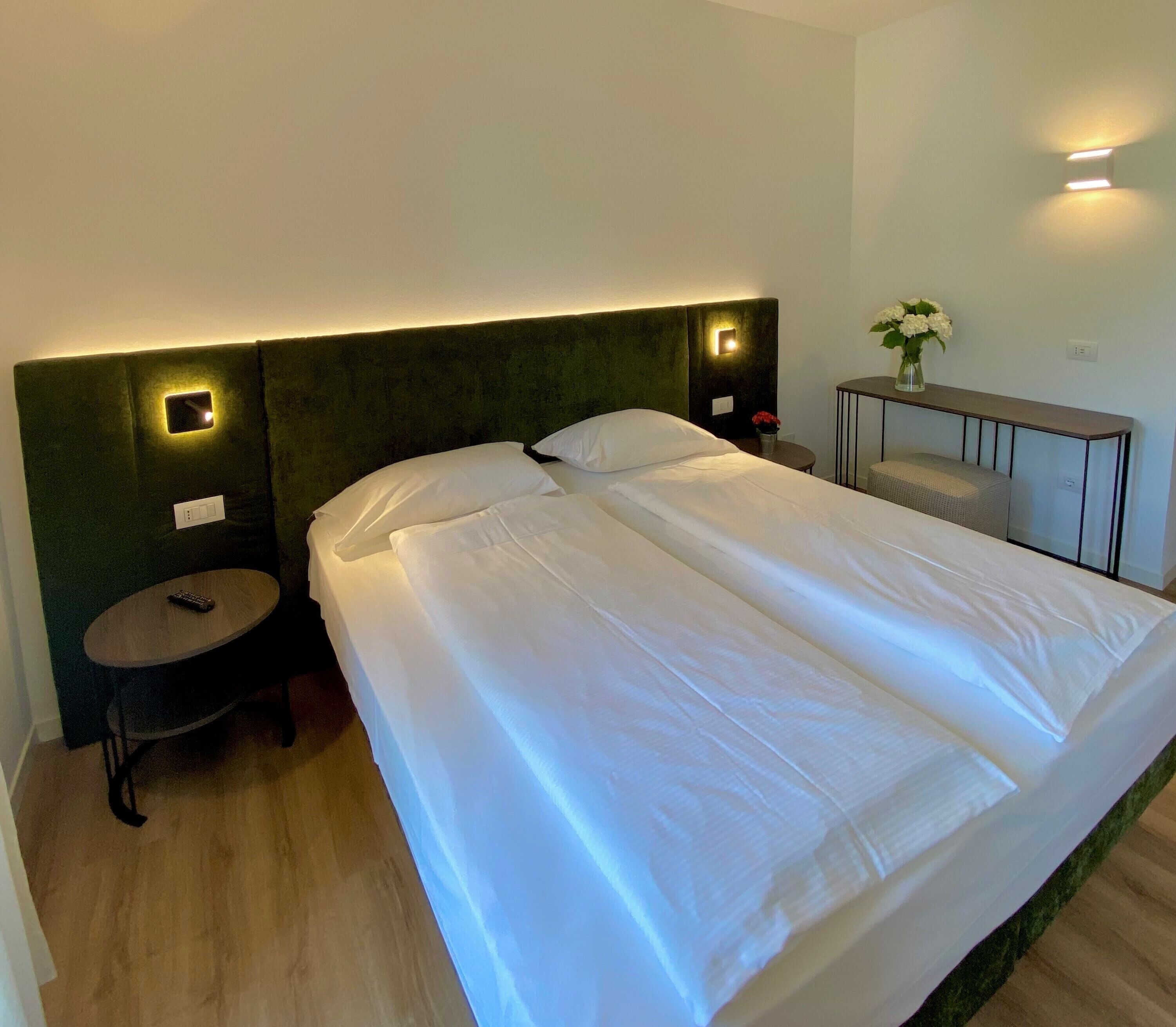 A hotel room with a large bed, two bedside tables, a small round table, and a nightstand.