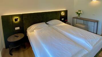 A hotel room with a large bed, two bedside tables, a small round table, and a nightstand.