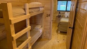 Een houten hut met stapelbedden en een eenpersoonsbed.