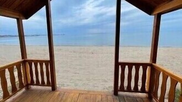 Een houten strandhut met uitzicht op het strand en de zee.