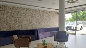 A lobby with a round coffee table, two armchairs, a sofa, and a patterned rug. - Hotel Cacuaco (Cacuaco)