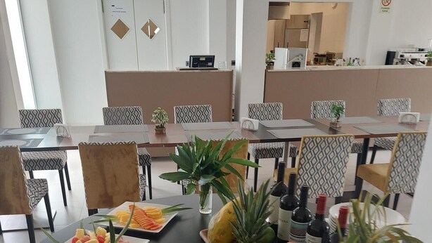 A dining area with round tables, some with plates of fruit and a bottle of wine. - Hotel Cacuaco (Cacuaco)