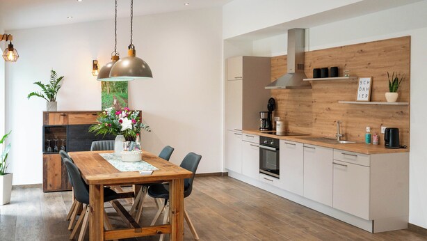Una cocina moderna con gabinetes de madera, horno integrado y encimera de madera.