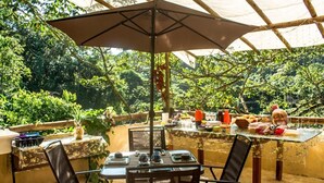 Un espace extérieur aménagé pour prendre les repas, avec une table, des chaises et un parasol.