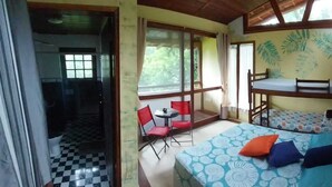 Une chambre avec des lits superposés, une petite table avec des chaises et une fenêtre donnant sur un paysage verdoyant.