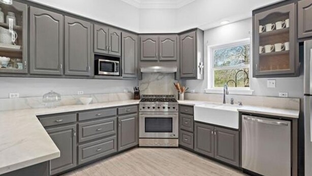 A modern kitchen with grey cabinetry, a stainless steel stove, and a window with a view of greenery. - Peaceful country getaway on a 2 acre pond (Folsom)