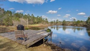 A wooden dock extending over a calm lake, with a chair and grill on the dock. - Peaceful country getaway on a 2 acre pond (Folsom)