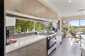 Enjoy cooking with a view in this kitchen featuring sleek cabinetry, ample counter space, and a large window overlooking the surrounding landscape.