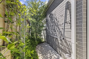 Stroll through this charming outdoor corridor, lined with lush foliage and a wooden fence.