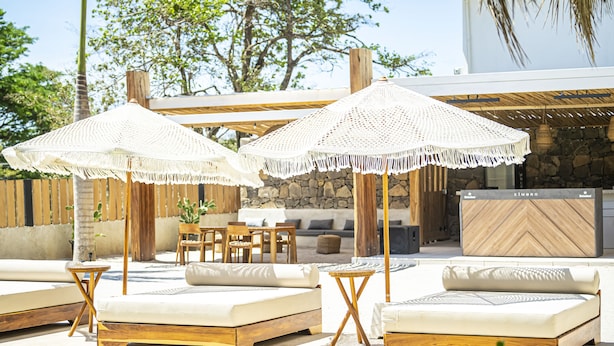 Een zwembadterras met ligbedden en witte, gehaakte parasols.