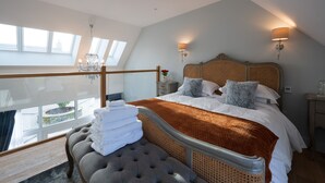 A bedroom with a large bed, a chaise lounge, a balcony with a view, and a chandelier. - Luxury one Bedroom Country Steading (Perth)