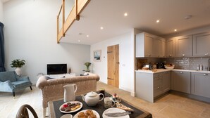A modern kitchen with a dining area, a sofa, and a TV. - Luxury one Bedroom Country Steading (Perth)