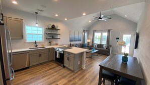 Une cuisine moderne dotée d’un îlot central, de planchers en bois et d’un ventilateur de plafond.