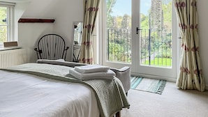 A bedroom with a bed, a chair, a radiator, and a view of the garden through a door. - 3 bedroom accommodation in Haverfordwest (Haverfordwest)