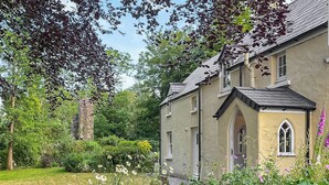 A traditional house with a garden, a stone wall, and a small arched window. - 3 bedroom accommodation in Haverfordwest (Haverfordwest)