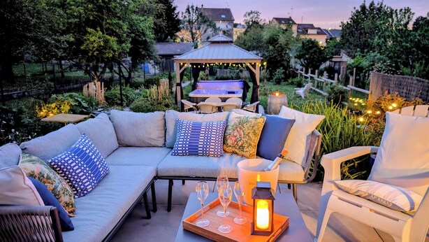 A patio with a sofa, chairs, a table with wine glasses, and a lantern. - Le Cémarose Charming cottage in Champagne near Epernay (Épernay)