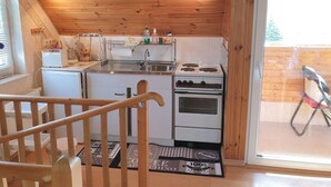 Kompakti keittiö, jossa on puuseinät, sisäänrakennettu liesi ja pesuallas.