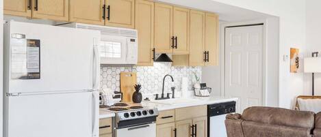 A kitchen with wooden cabinets, a white refrigerator, a microwave, a stove, and a dishwasher.