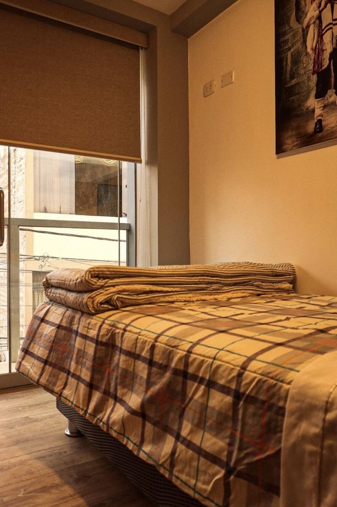 Una camera da letto con un letto, una finestra con una tenda e un quadro appeso al muro.