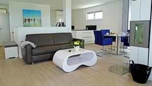 Un salon moderne comprenant un canapé, une table basse et un coin repas avec des chaises et une table.