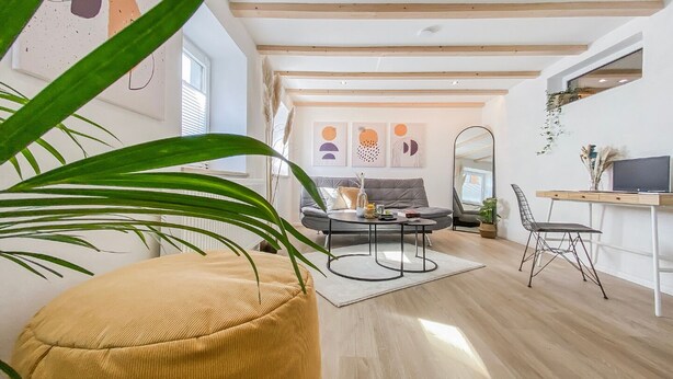 Un salon moderne comprenant un canapé, une table basse et un coin repas avec un bureau et une chaise.