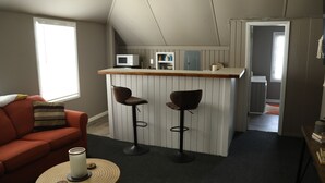 A compact living space with a kitchenette, a sofa, two bar stools, and a small round table. - NEW - Private Downtown Christiansted Apartment (Christiansted)