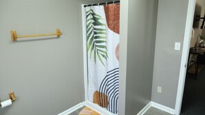 A bathroom with a shower curtain featuring a leaf pattern, a towel rack, and a toilet paper holder. - NEW - Private Downtown Christiansted Apartment (Christiansted)