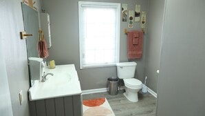 A bathroom with a white sink, a toilet, a window with blinds, and a mirror. - NEW - Private Downtown Christiansted Apartment (Christiansted)