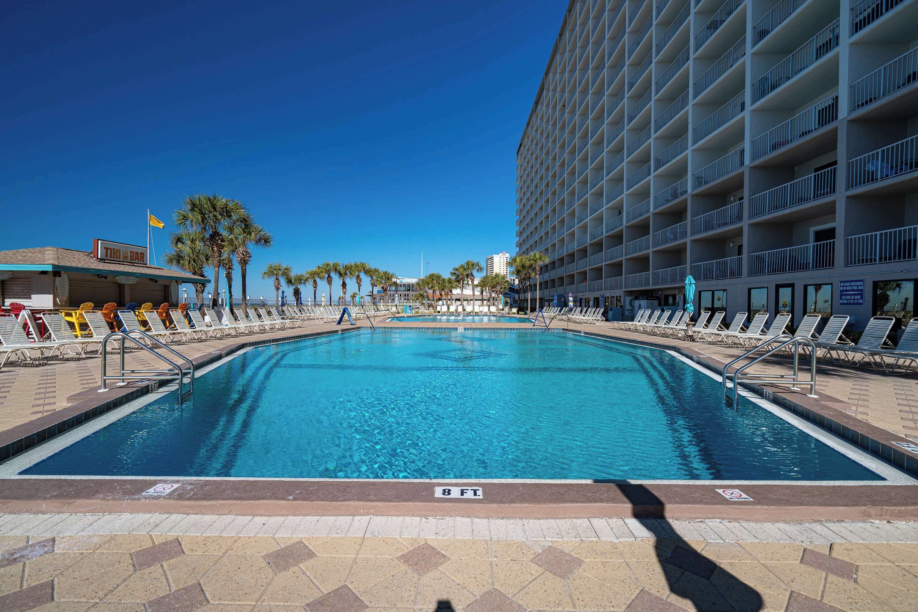 A swimming pool with lounge chairs and a building with balconies.