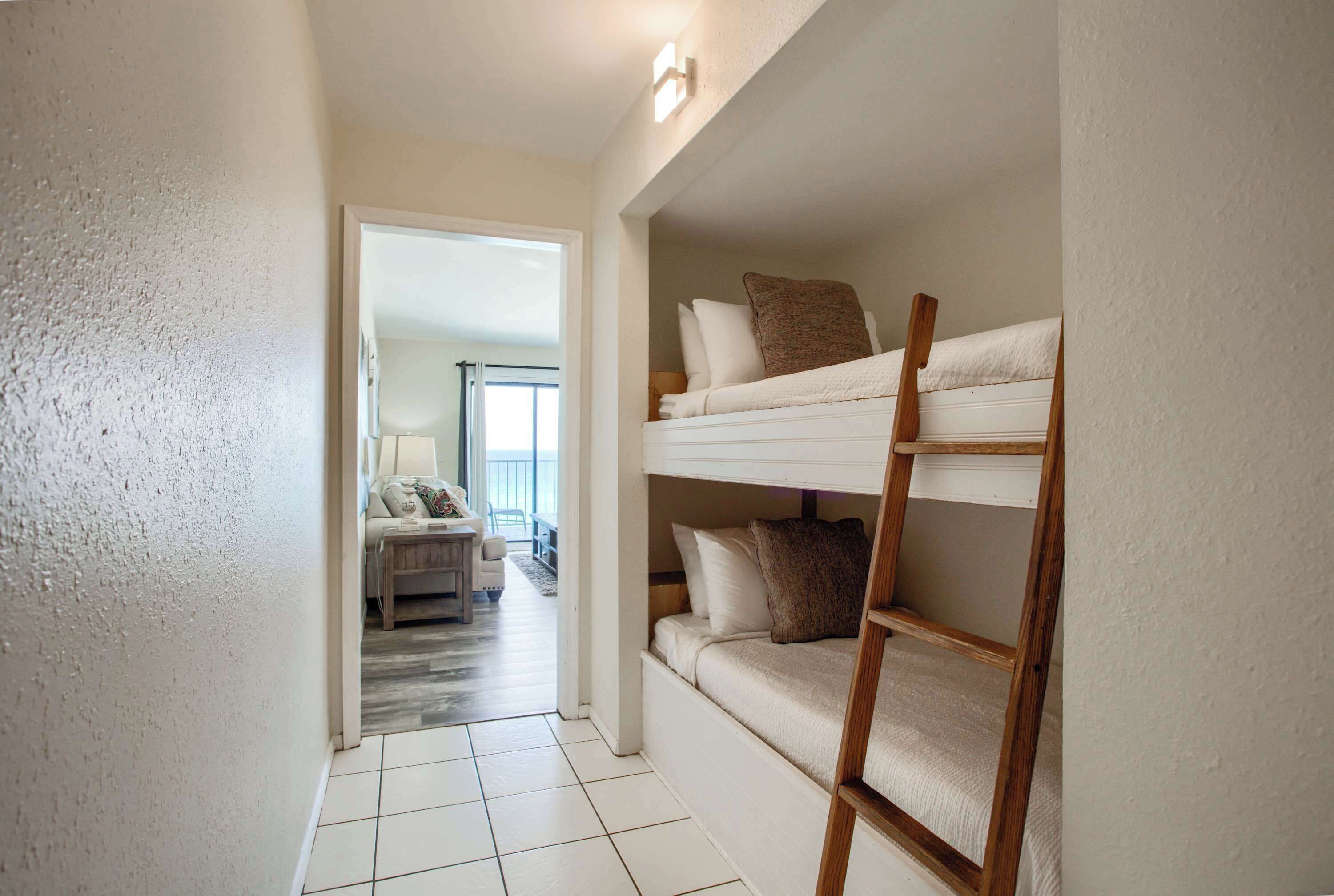 A bunk bed with a ladder, a sofa, and a lamp in a hallway.