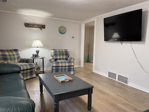 Relax in this inviting living room with a comfortable sofa, armchair, and mounted TV.