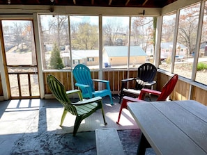 Relax in a serene outdoor space with a view of the surrounding neighborhood, featuring a table and Adirondack chairs.