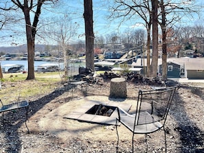 Relax by the fire pit surrounded by trees and a serene lake view.