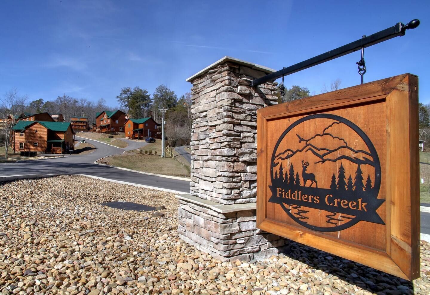 A wooden sign with a mountain and deer logo for Fiddlers Creek.