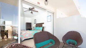 A bedroom with a bed, a ceiling fan, and two wicker chairs.