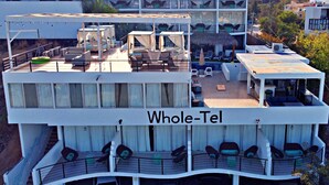 A multi-story hotel with outdoor seating areas, balconies, and a parking area.