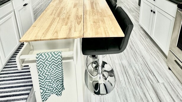 Una cucina moderna con isola centrale, sedie nere e una ventola a soffitto.