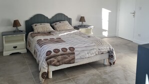 A bedroom with a bed, two nightstands, a lamp, and a door.