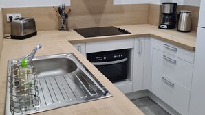 A modern kitchen with a built-in oven, a toaster, a coffee maker, and a sink with a dish rack.