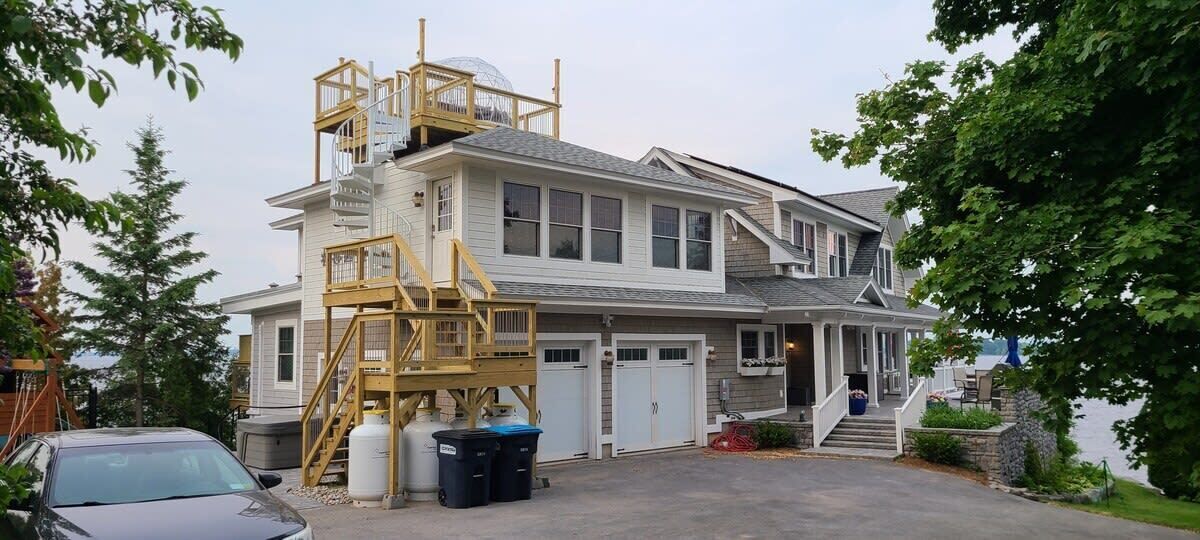 Une maison à deux étages avec un grand garage, une terrasse en bois et un escalier menant au deuxième étage.