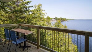 A wooden deck with a table and chairs overlooking a lake.