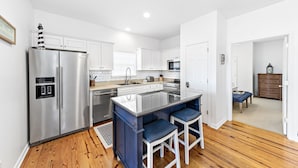 A modern kitchen with white cabinets, stainless steel appliances, and a central island with bar stools.