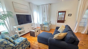 A living room with a TV, two sofas, a coffee table, and a patterned armchair.