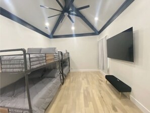 A room with bunk beds, a ceiling fan, a flat-screen TV, and a bench. - Entire Luxury Home to Enjoy Dallas: Howdy Haven (Dallas)